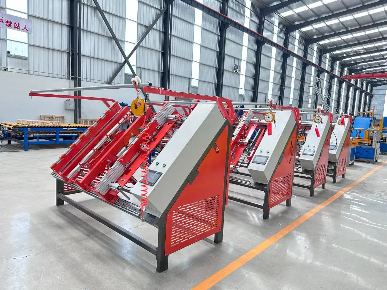 Row of red pallet nailing machines in a factory hall