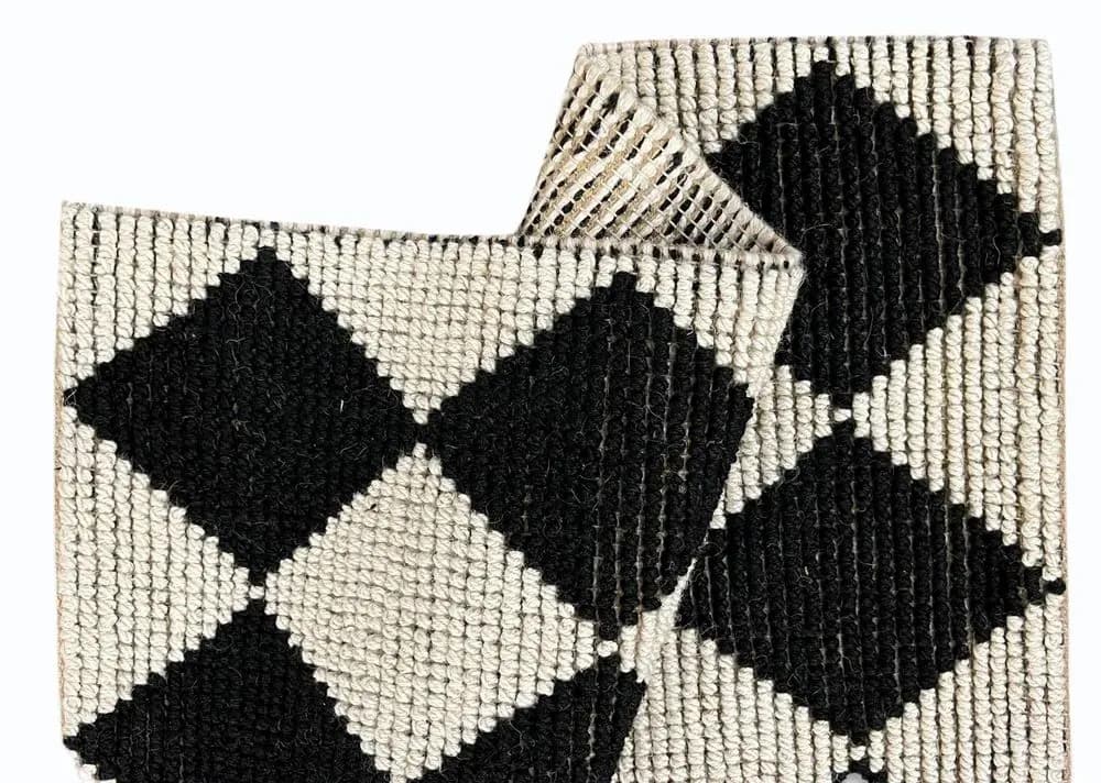 Black and white diamond pattern woven rug, folded
