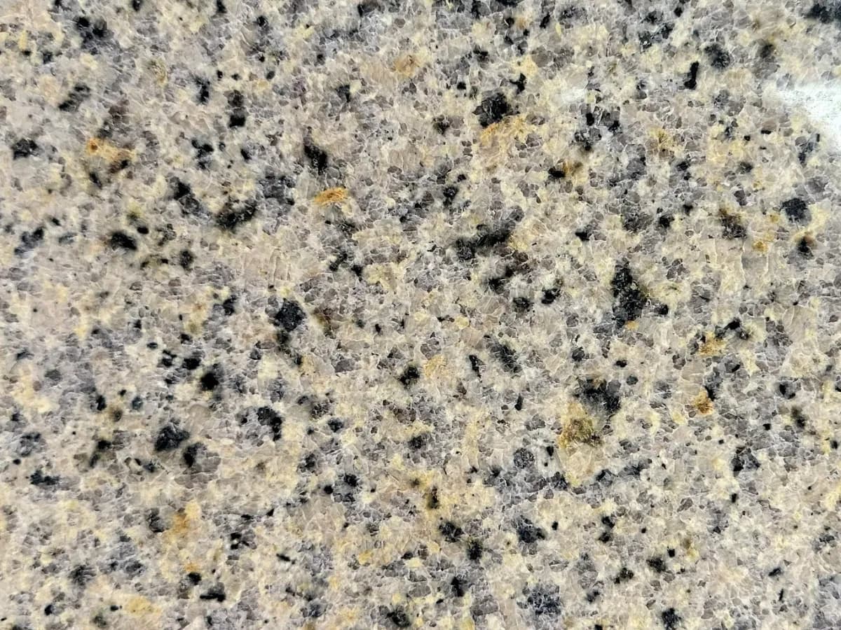Polished light yellow granite surface with black and gray speckles