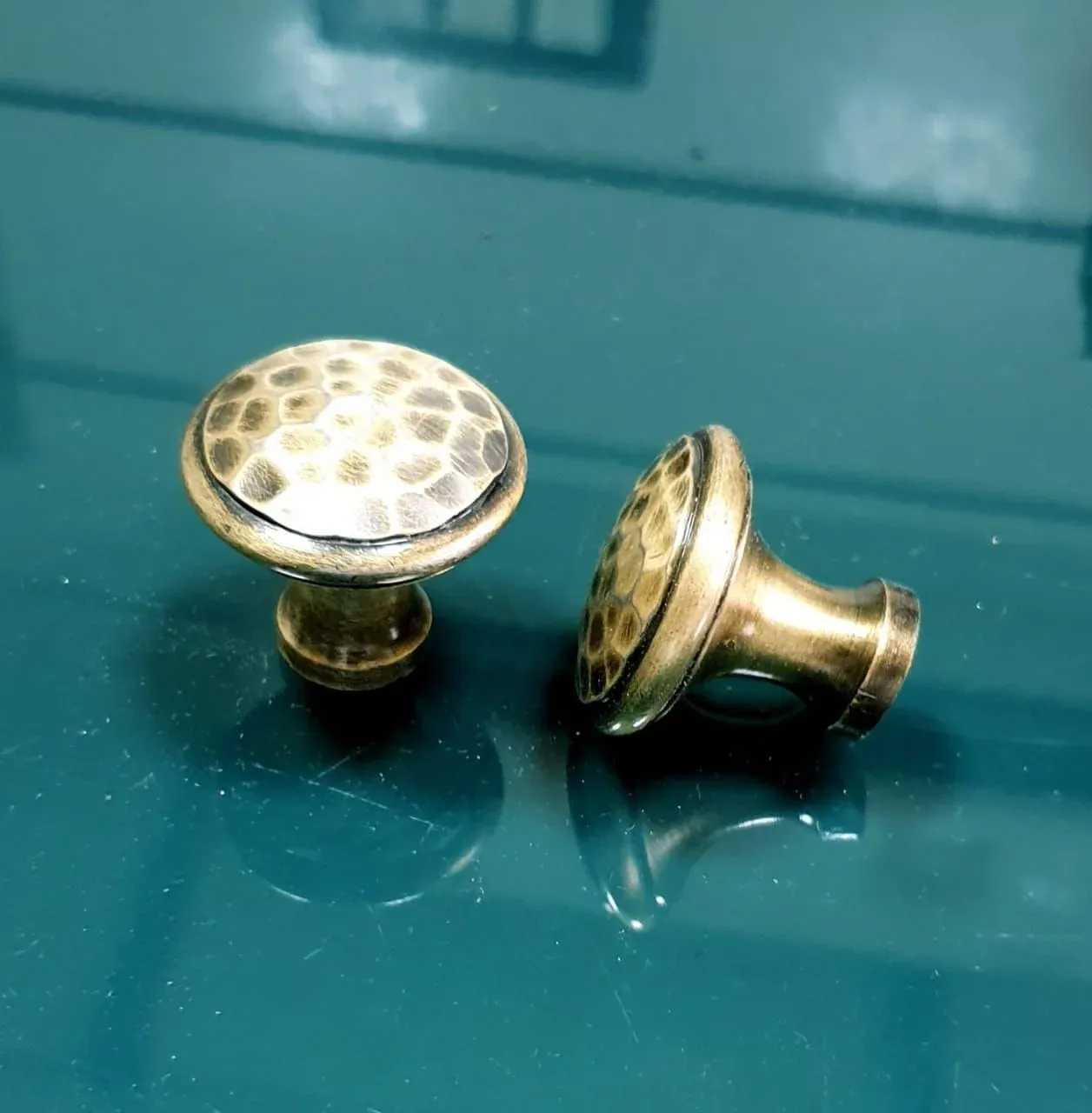 Hammered round cabinet knobs on a teal surface