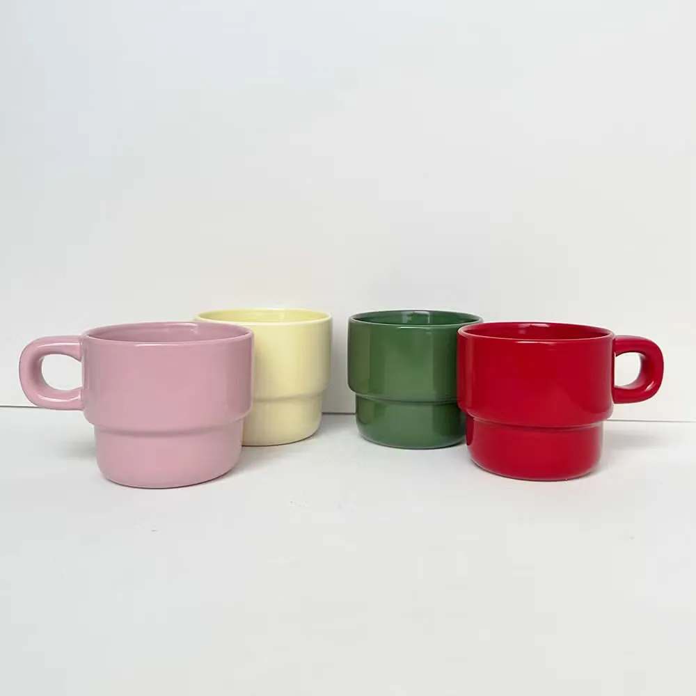 Four stackable ceramic mugs in pink, cream, green and red