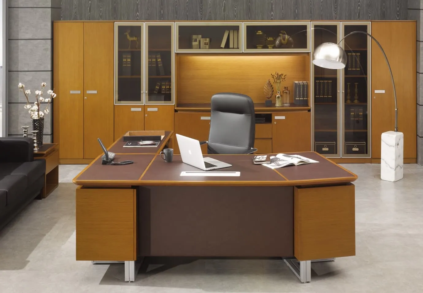 Executive office with a brown wood and leather desk, tall bookcases and a black chair